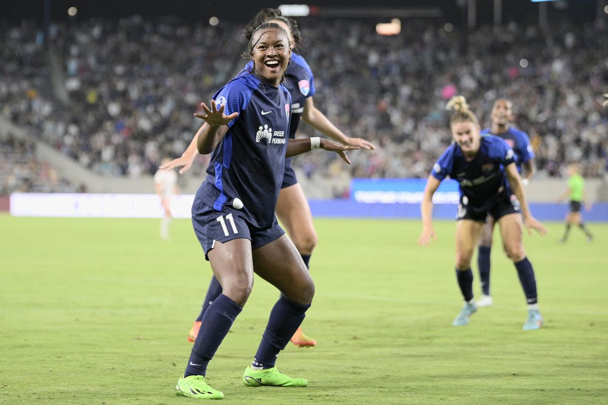 NWSL: Angel City FC at San Diego Wave FC. Jaedyn Shaw strikes a pose as part of her goal celebration vs. Angel City in her navy blue and pink home kit. Teammates Christen Westphal, Taylor Kornieck and Naomi Girma also celebrate in a blurred background.