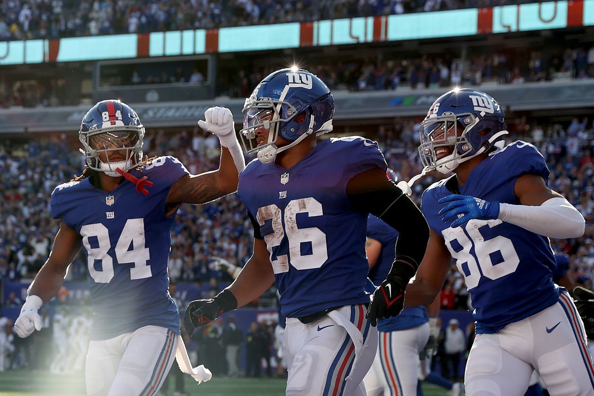 Marcus Johnson #84 and Darius Slayton #86 of the New York Giants congratulate Saquon Barkley #26 after he scored a touchdown in the fourth quarter against the Baltimore Ravens at MetLife Stadium on October 16, 2022 in East Rutherford, New Jersey.