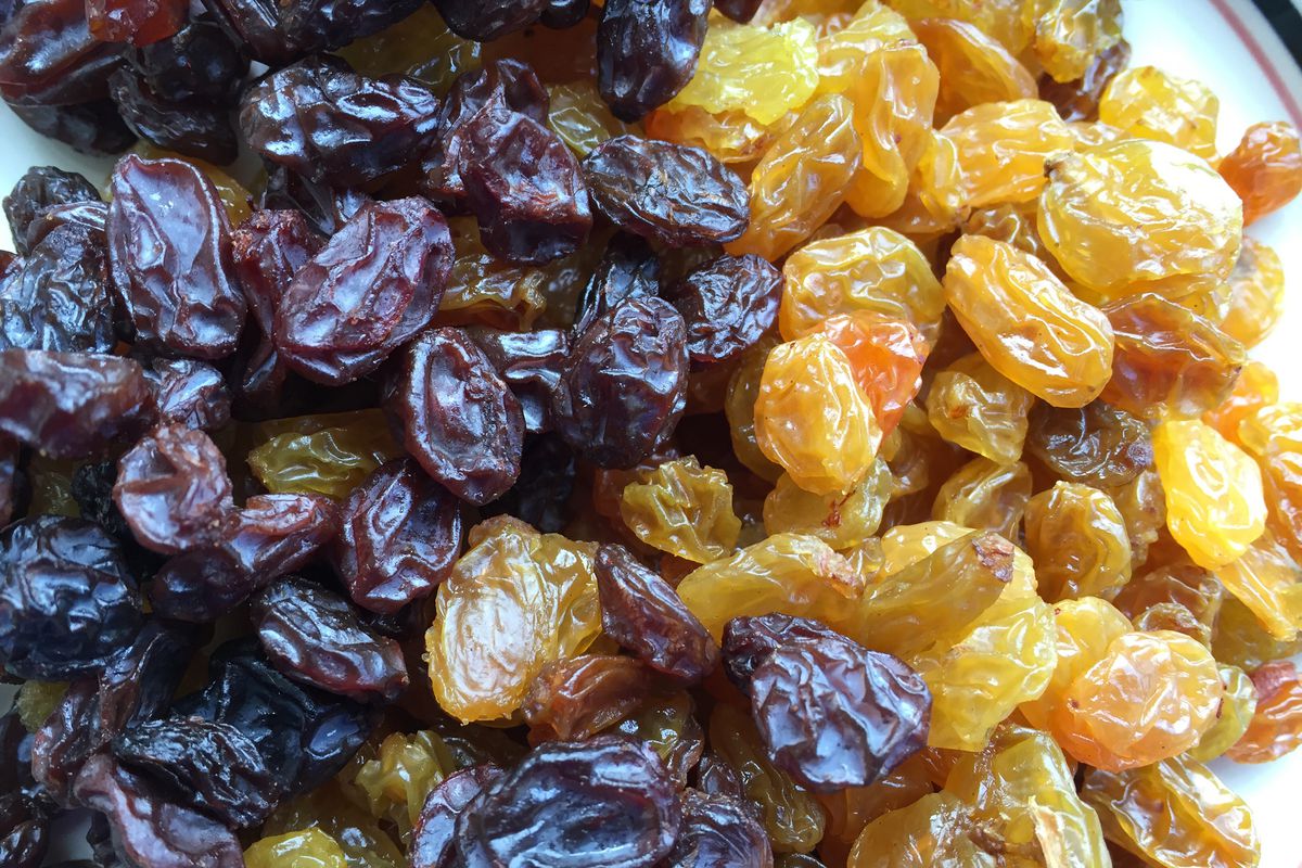 A close-up of black and golden raisins