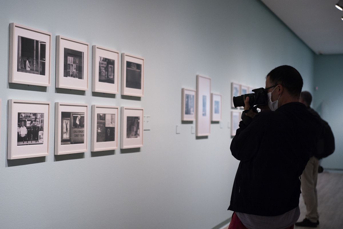 a person takes a photo of eight photographs on the wall at an art gallery