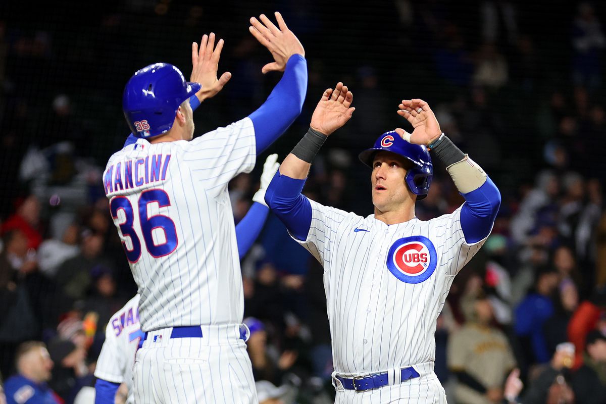 Yan Gomes and Trey Mancini of the Chicago Cubs celebrate after scoring a run on a three-RBI triple by Nico Hoerner during the eighth inning against the San Diego Padres at Wrigley Field on April 25, 2023 in Chicago, Illinois.