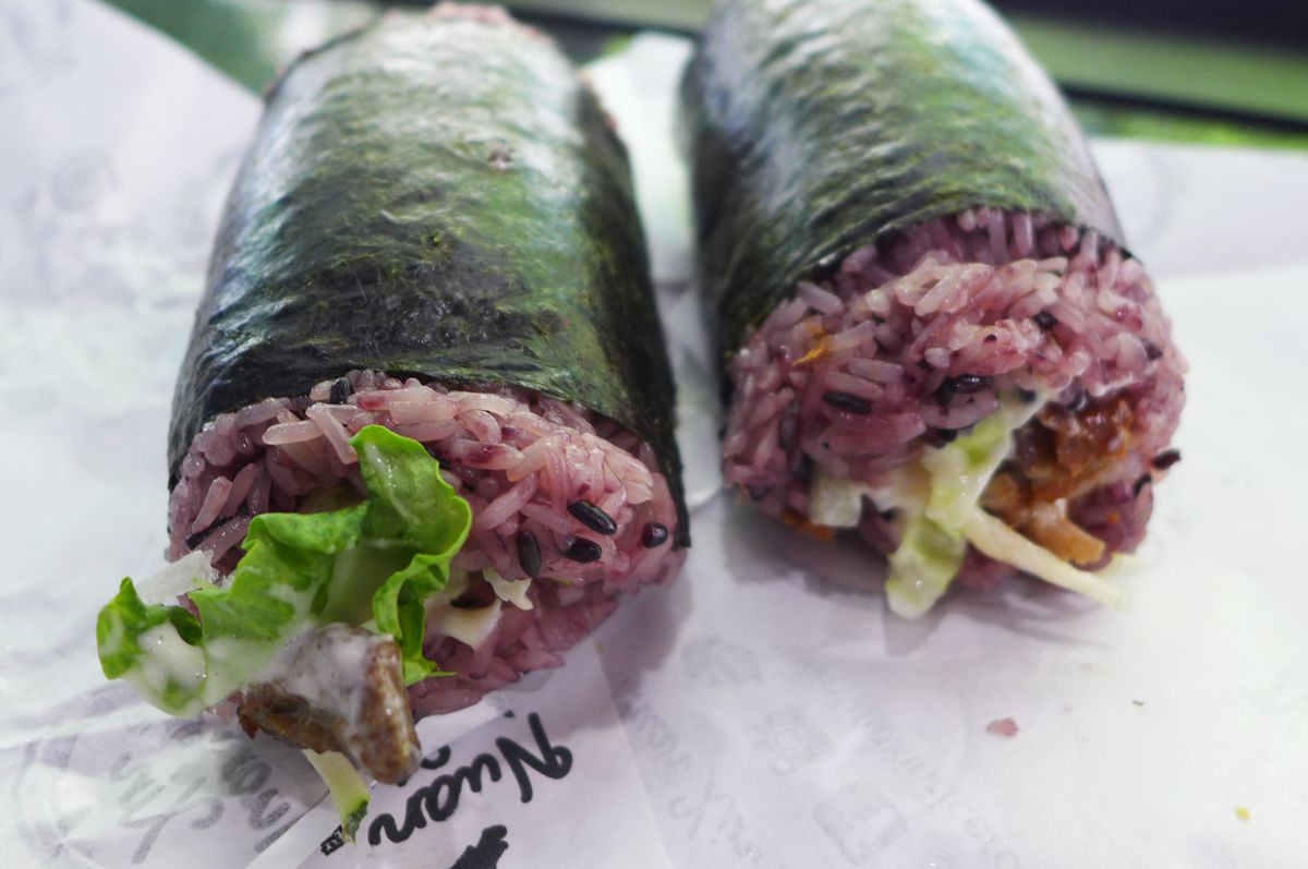 Two pudgy rolls with purple rice and lettuce showing at the ends.