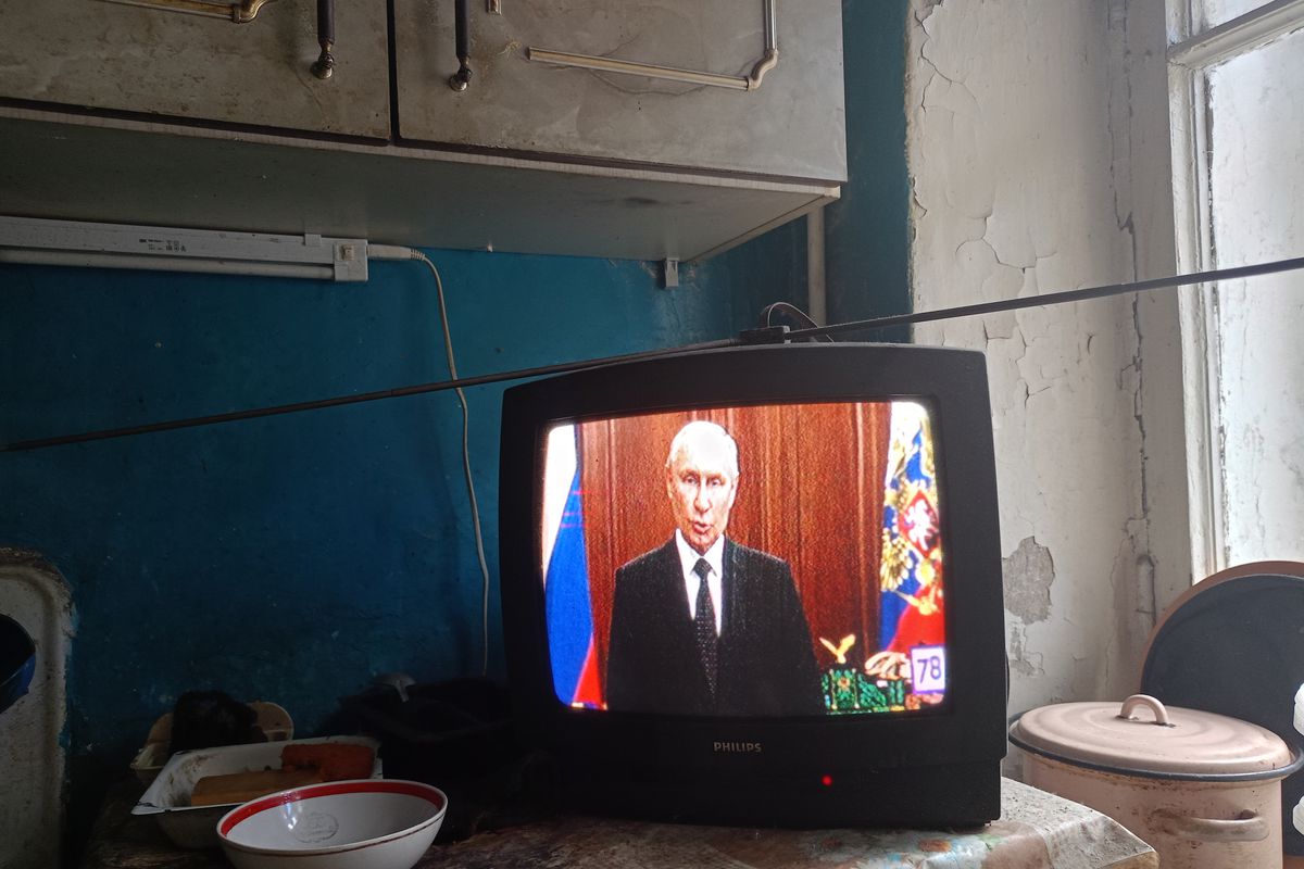 A TV screen showing Putin. 