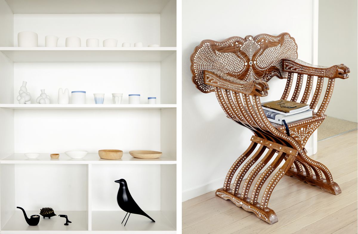 Left: An open shelving unit with ceramics and trinkets. Right: An intricately designed wooden chair with some books sitting on it. 