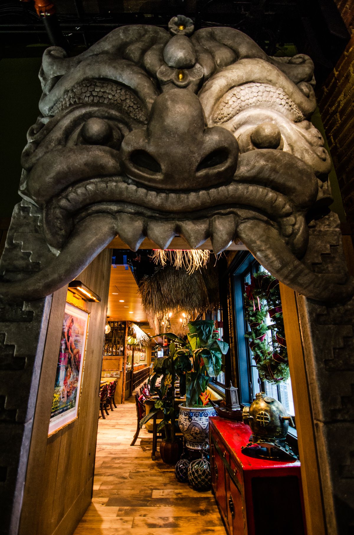 An entryway sculpted to look like a stone face leads into a tiki-themed restaurant.