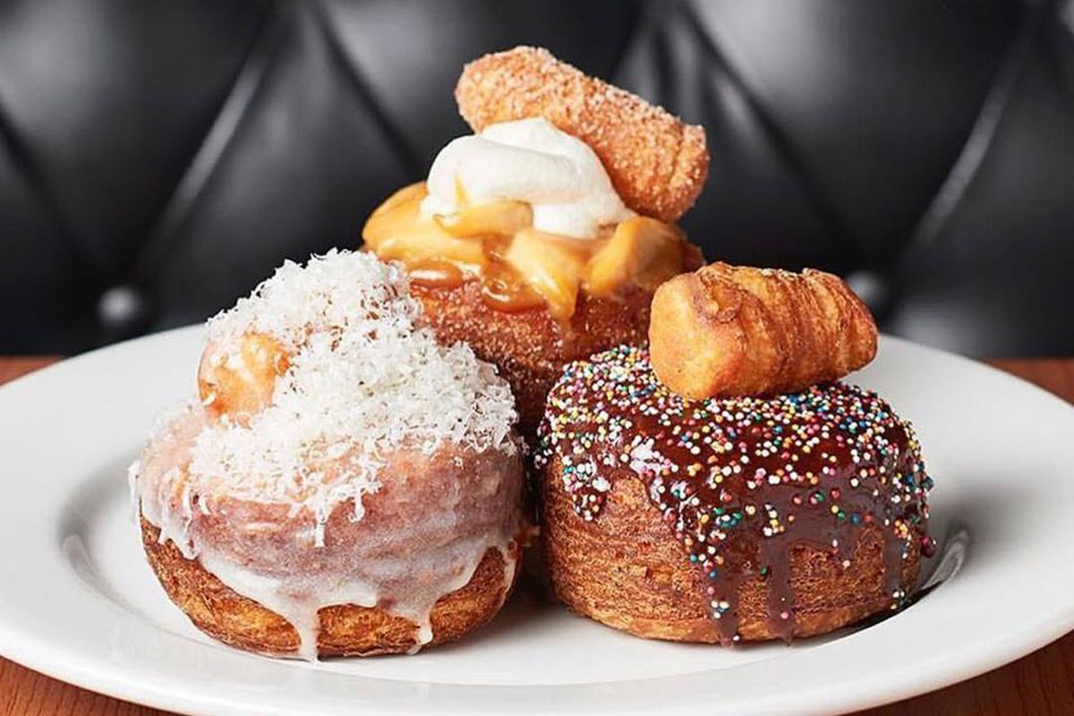 Three very large, multi-layered doughnuts with different toppings