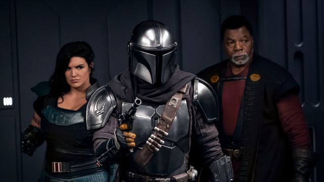 Cara Dune, The Mandalorian, and Greef Karga stand in an elevator with their blasters up