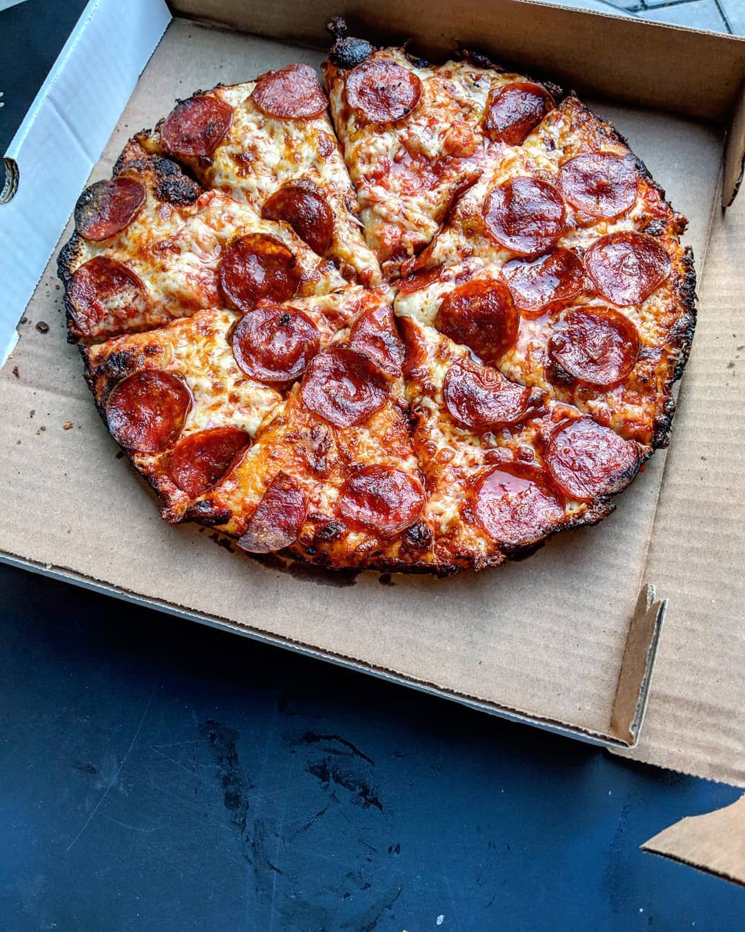 Overhead view of a pepperoni pizza in the style of Massachusetts’ South Shore-style bar pizza, with a barely-there, lacy, charred edge and bubbly brown cheese spots