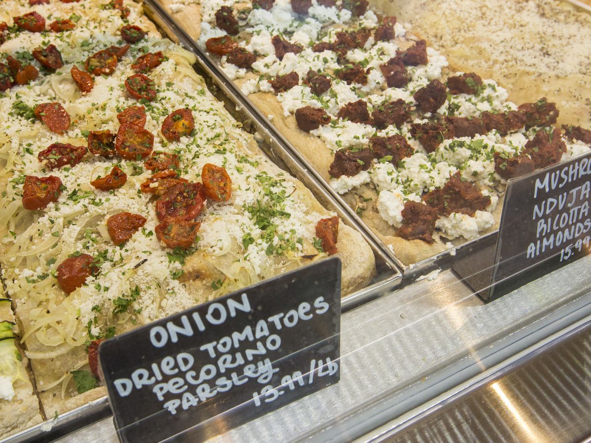 A display case full of uncut square pizza pies.