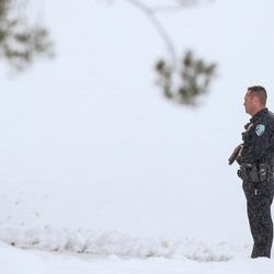 A police officer stands with his sidearm drawn outside Mueller Park Junior High School in Bountiful as law enforcement officers respond to a shooting on Thursday, Dec. 1, 2016.