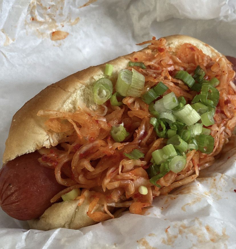 Firedog — a plump beef hot dog topped with spring onions, gochujang, and a generous portion of shredded green cabbage kimchi at Hankook Taqueria in Atlanta. 