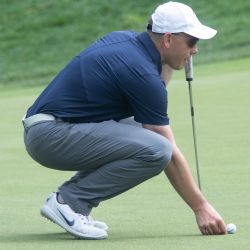 UConn men’s hockey coach Mike Cavanaugh lines up his putt at the 9th hole.