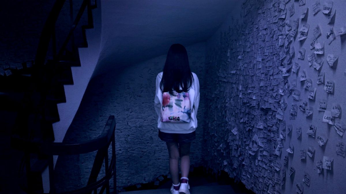 Maya in Silent Hill: The Short Message with her back to us. She’s in a dark stairwell and the walls are covered in white notes. She’s wearing a white jacket and a skirt.