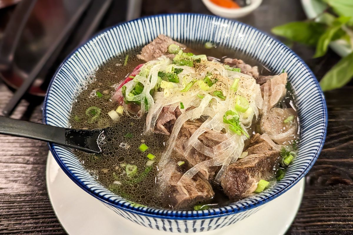 Bowl of Vietnamese beef noodle soup topped with sliced onions.