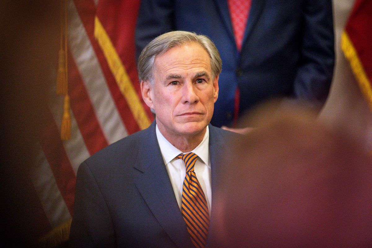 Greg Abbott, wearing a suit and with American flags behind him, is seen facing an audience