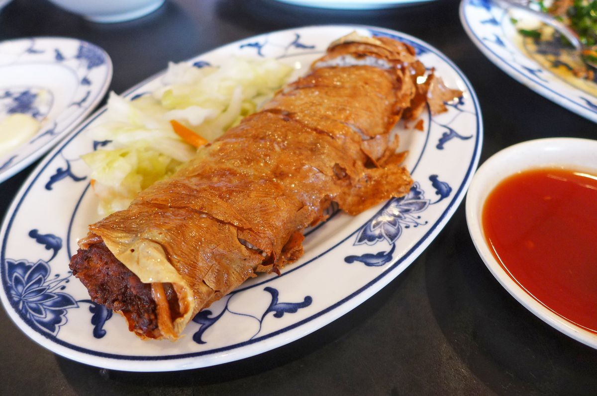 A roll of crisp fried tofu stuffed with meat, served in slices.