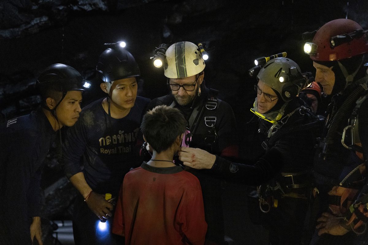 Mağaracılık kaskları takan bir grup adam bir çocuğun yanında duruyor.