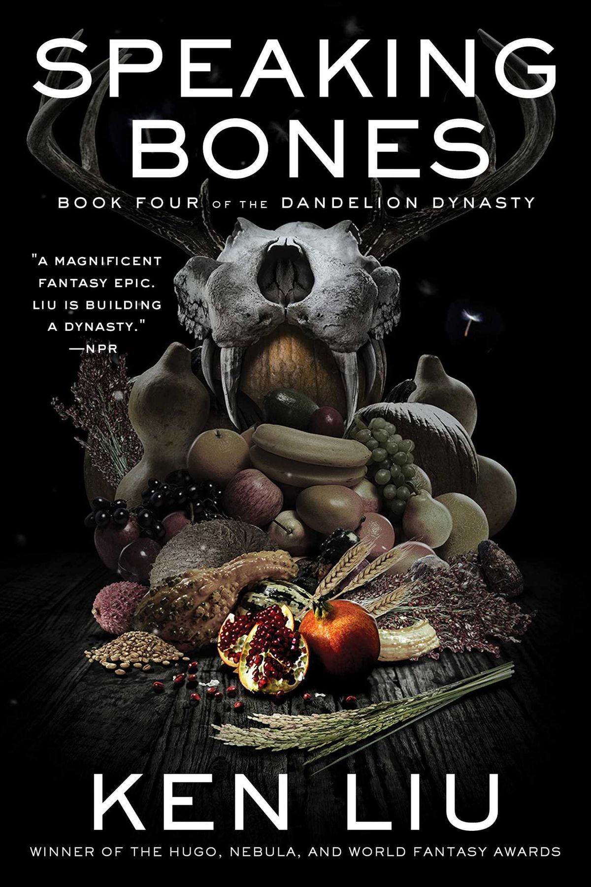 The cover for Speaking Bones showing a feast on a table, with and a skull with antlers at the back