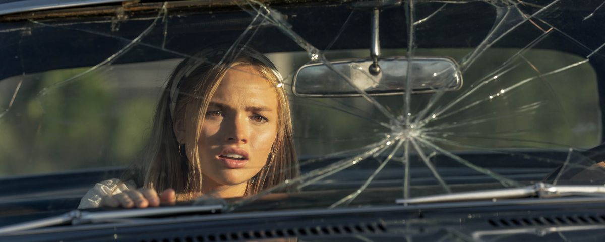 Norma (Natalie Alyn Lind), a young blonde woman, sits in a car with a smashed windshield, a worried expression on her face, in Pet Sematary: Bloodlines