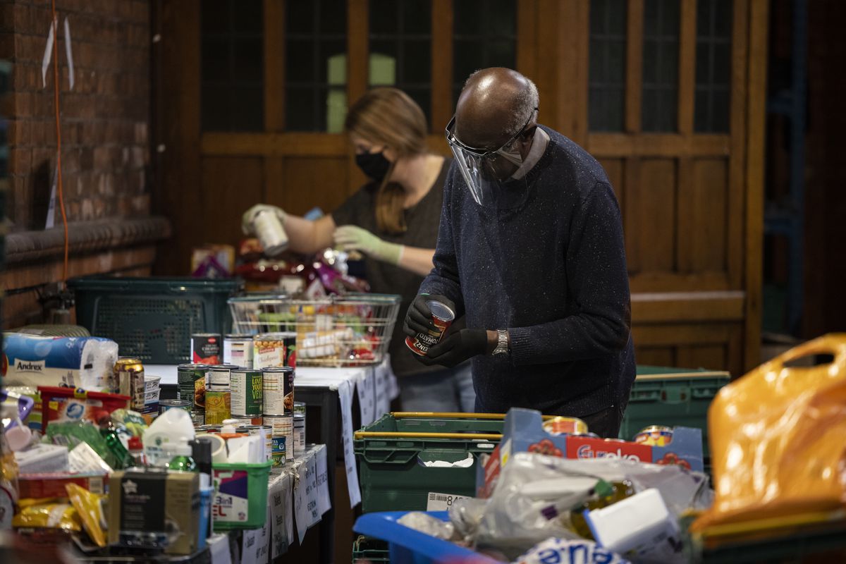 Trussell Trust volunteers stand over crates of food, packing food parcels for London food banks
