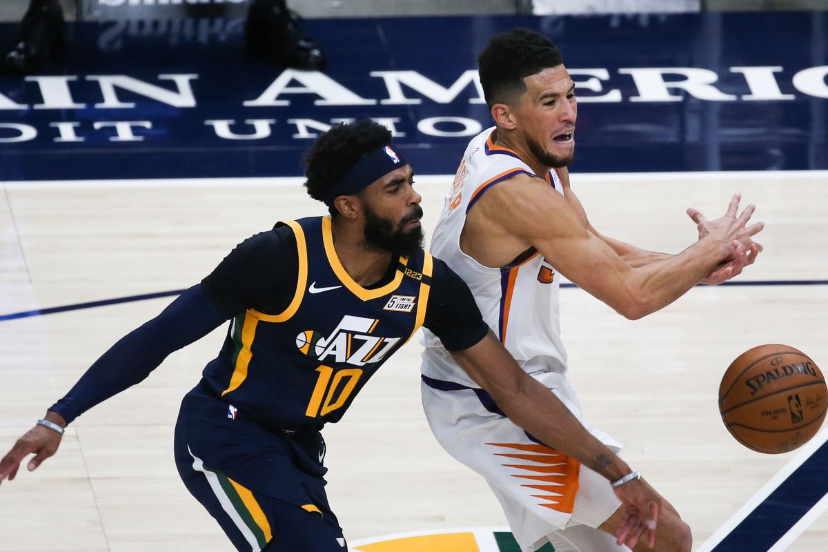 Utah Jazz guard Mike Conley (10) blocks the dribble from Phoenix Suns guard Devin Booker (1) during an NBA basketball game at Vivint Smart Home Arena in Salt Lake City on Thursday, Dec. 31, 2020.
