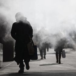 A pedestrian walks through the exhaust of a steam vent during a frigid morning commute, Friday, Feb. 20, 2015, in New York. Arctic air and bitterly cold wind is moving across the Northeast, plunging temperatures into record low single digits, accompanied by subzero wind chills. 