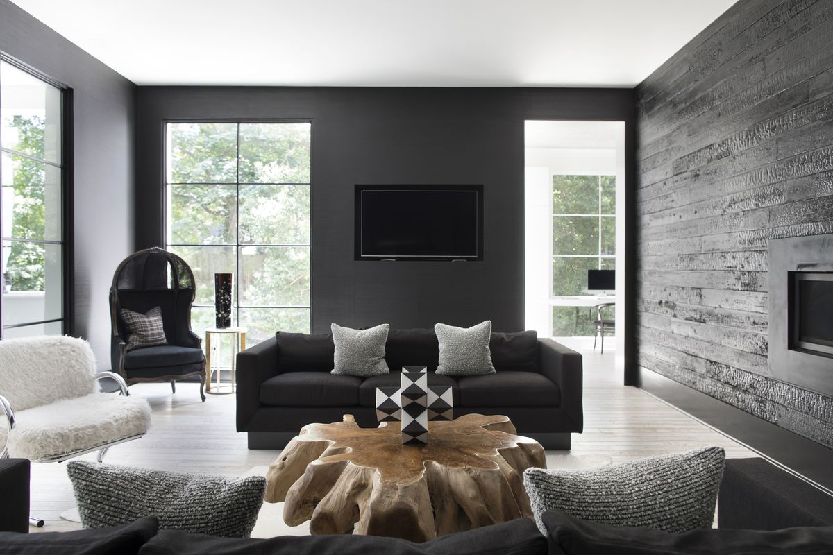 A dark gray sofa with a low back and two light gray cushions sits in the middle of a mostly monochromatic room. 