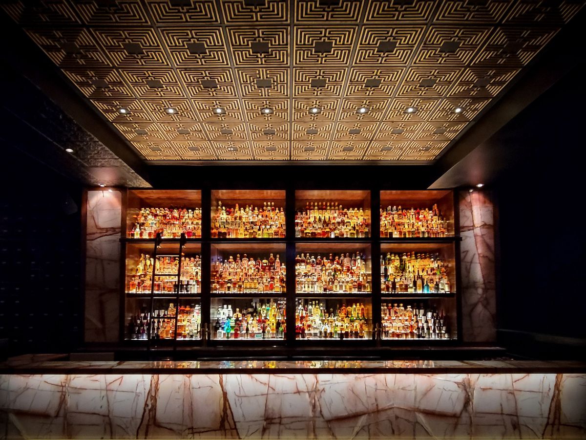A large pink marble bar backed by shelves of bottles.