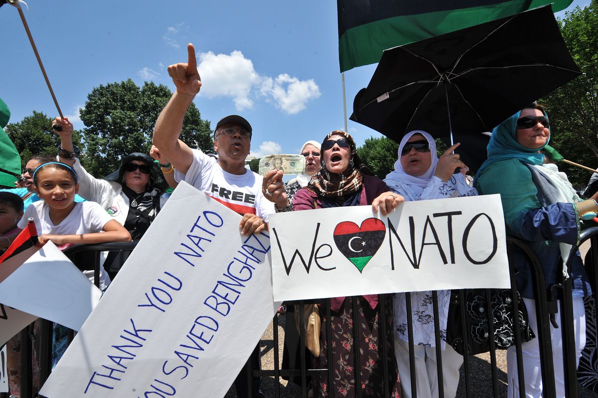 Opponents of Libyan leader Muammar Qaddafi hold signs in front of the White House in Washington on July 9, 2011, during opposed demonstrations against Qaddafi and the NATO bombing of Libya. 