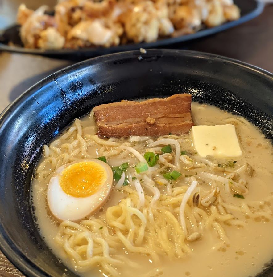 Shio ramen topped with egg and chashu, with a pile of fried chicken fuzzy in the background.