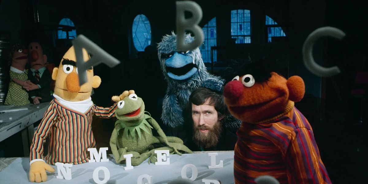 A young, bearded Jim Henson behind the scenes of a Sesame Street skit