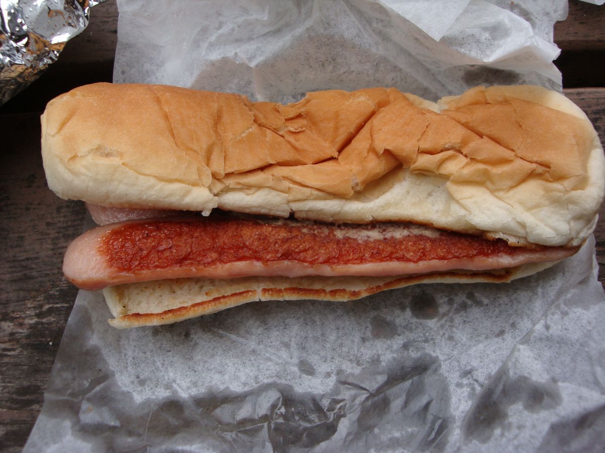 A split hot dog browned on the inner surface on a bun.