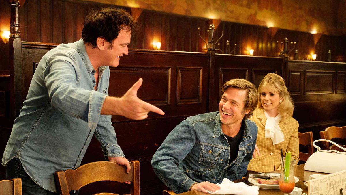 Quentin Tarantino gestures happily as Brad Pitt looks on.