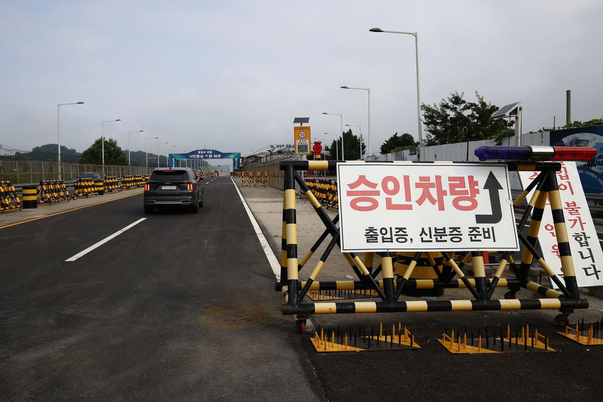 A two-lane blacktop road with a sign in Korean on a barricade beside it.