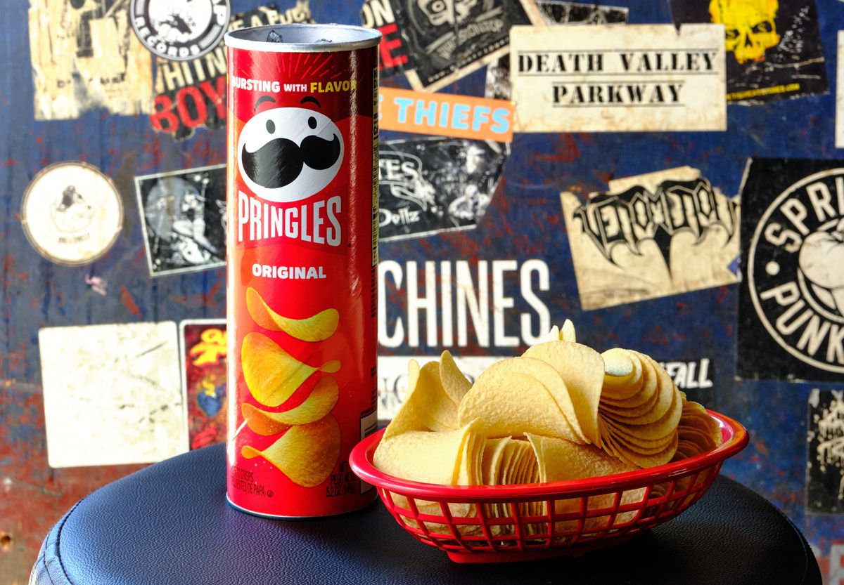 A can of Pringles filled with alcohol and a basket of Pringles chips on the side.