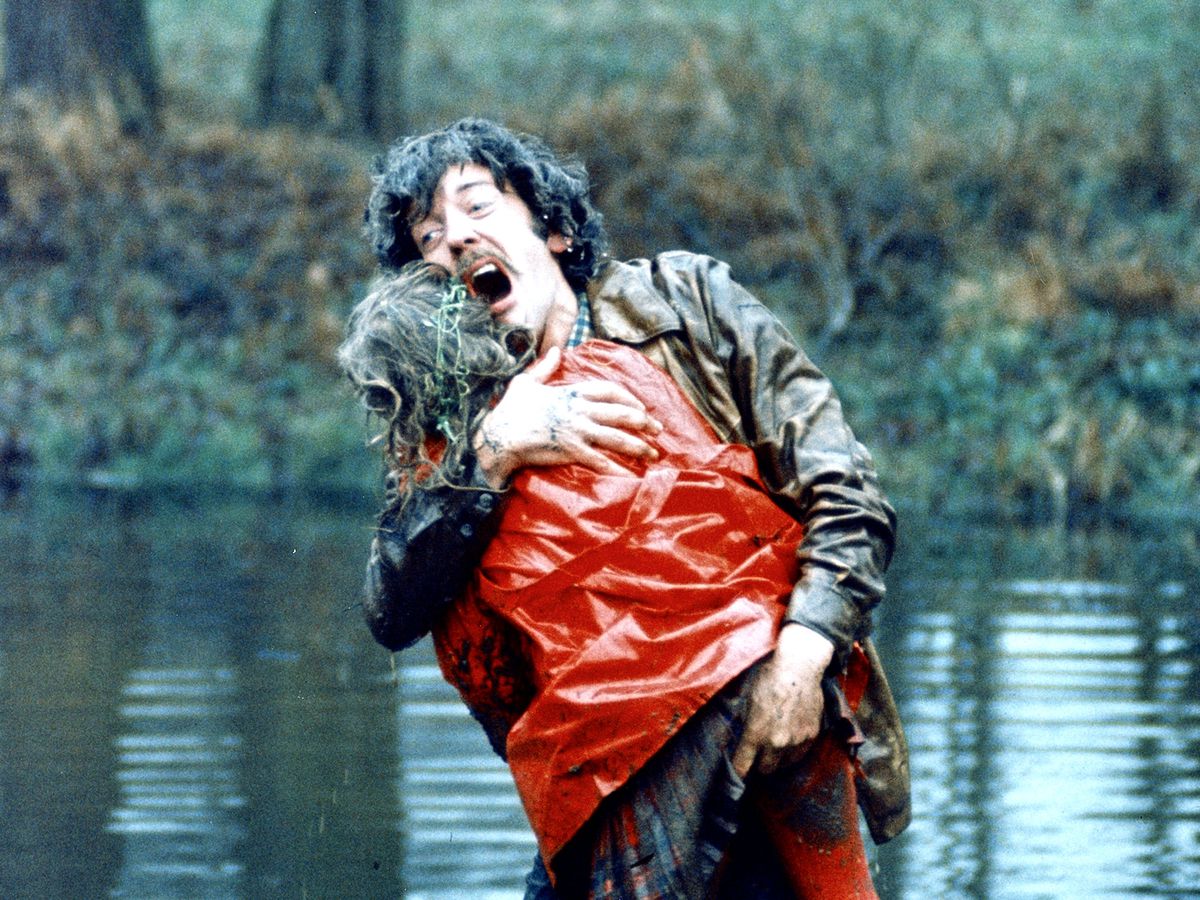 Donald Sutherland screams in grief while holding a lifeless figure in a red raincoat by a lake in Don’t Look Now