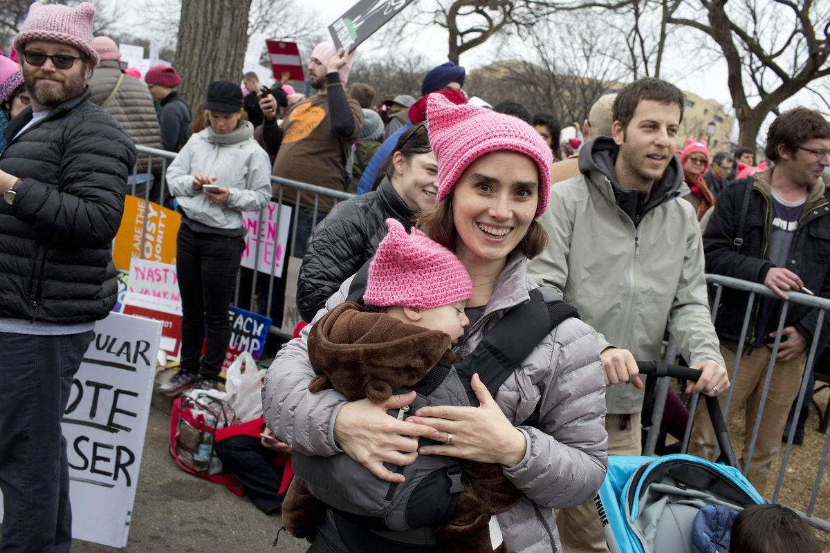 A smiling mother holds he young daughter at the women’s march following Trump’s inauguration