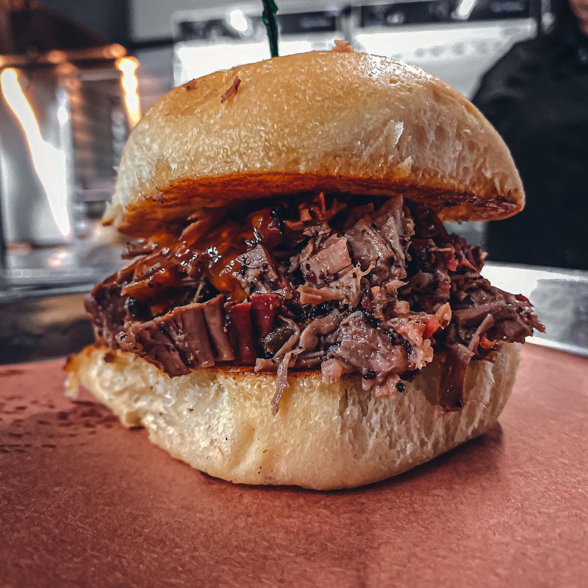 A sandwich with chopped beef brisket in between two bun halves on brown butcher paper.