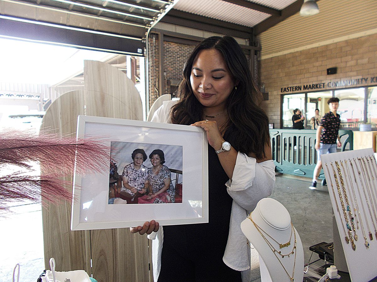 A woman showing off a framed photo of family members from her jewelry stand at the Night Market in Eastern Market in Detroit, Michigan.