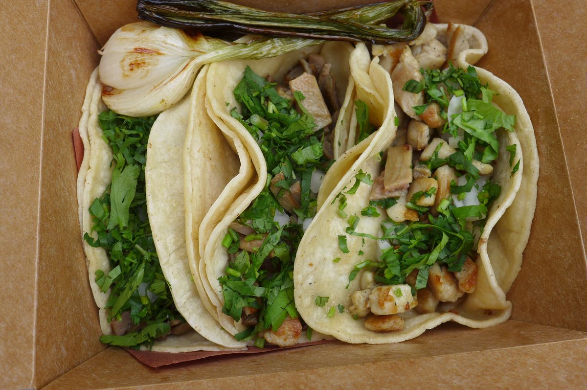 Three double-tortilla tacos in a cardboad box.
