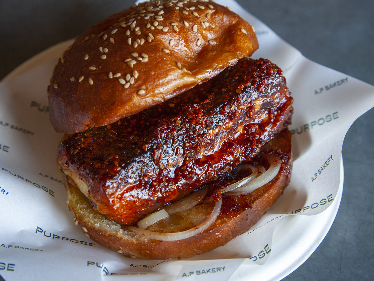 A hunk of red, hot honey-covered cheese inside a sesame bun. 