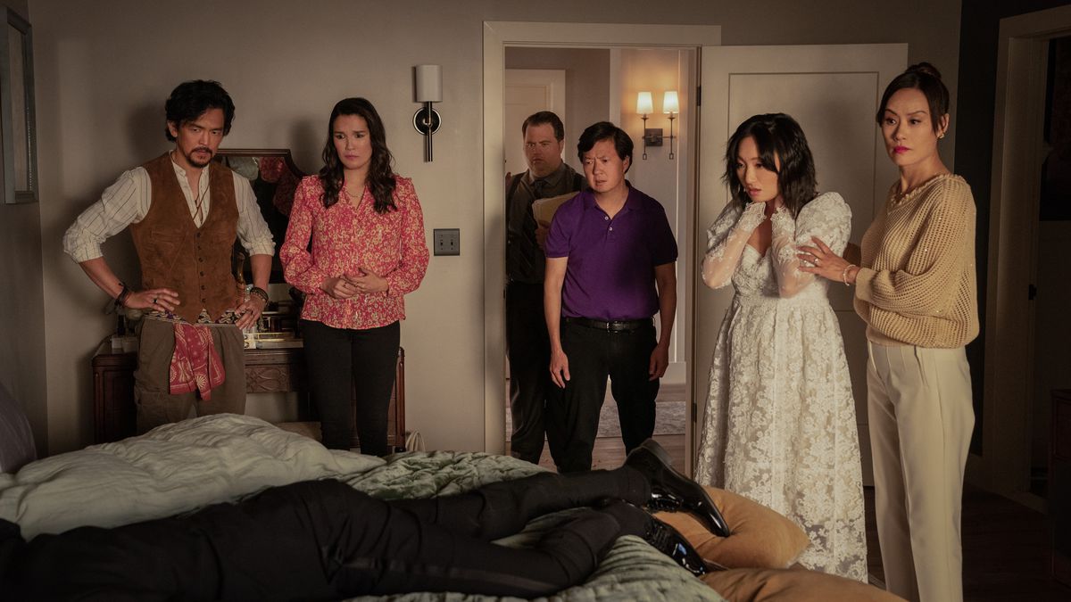 A bride and her shocked family stand over the bed where the torso of a dead man in a tux lies in season two of The Afterparty.
