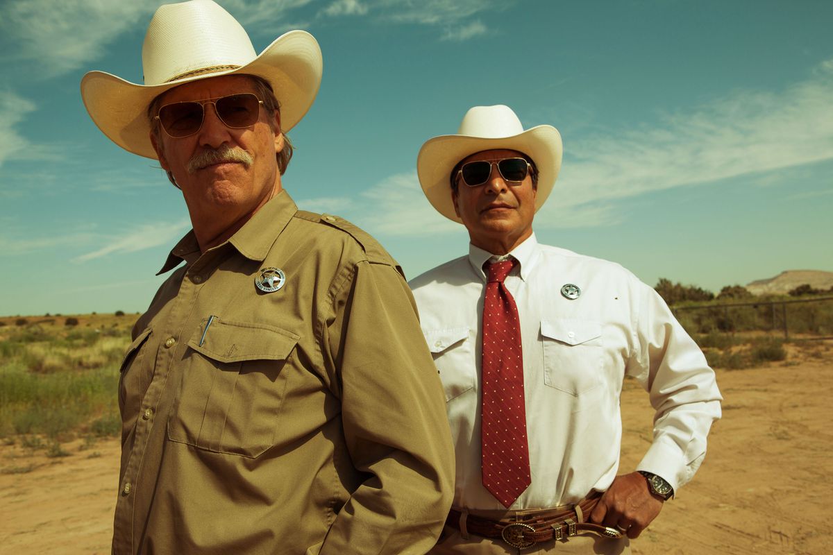 Jeff Bridges and Gil Birmingham in Hell or High Water. They both wear Texas Rangers outfits, with cowboy hats and sunglasses.