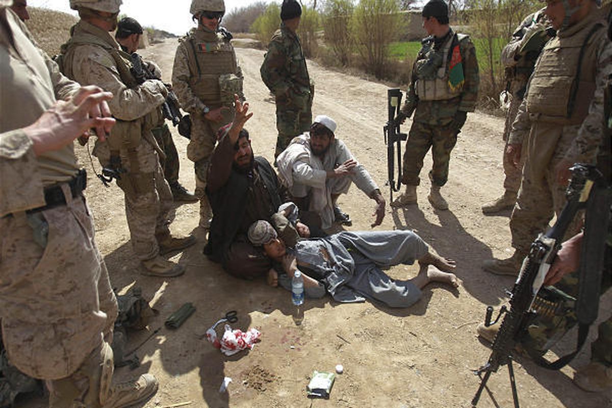 Afghan men bring a boy who they say was injured by an improvised explosive device set by the Taliban to a checkpoint manned by U.S. Marines from 3rd Battalion, 6th Marine Regiment and Afghan National Army soldiers for help in Marjah in Afghanistan's Helma