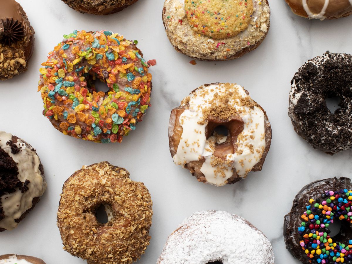 From above, an assortment of doughnuts with different toppings on a marble countertop