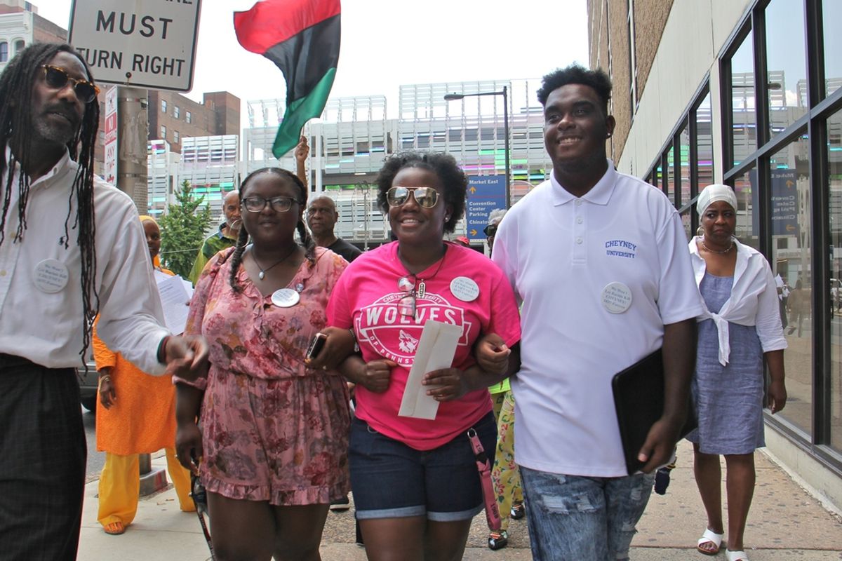 Cheyney students (from right) Shaquille Harrison, Nyrie Watson and Shaneka Briggs link arms as they make their way to Gov. Tom Wolf's Philadelphia office on Eighth Street to deliver a letter demanding funds for the struggling historically black university.