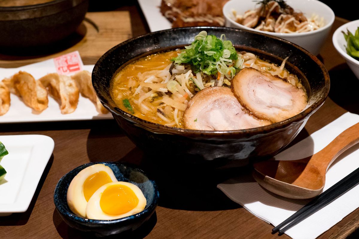 A bowl of ramen with soft-boiled egg halves in a bowl on the side. 