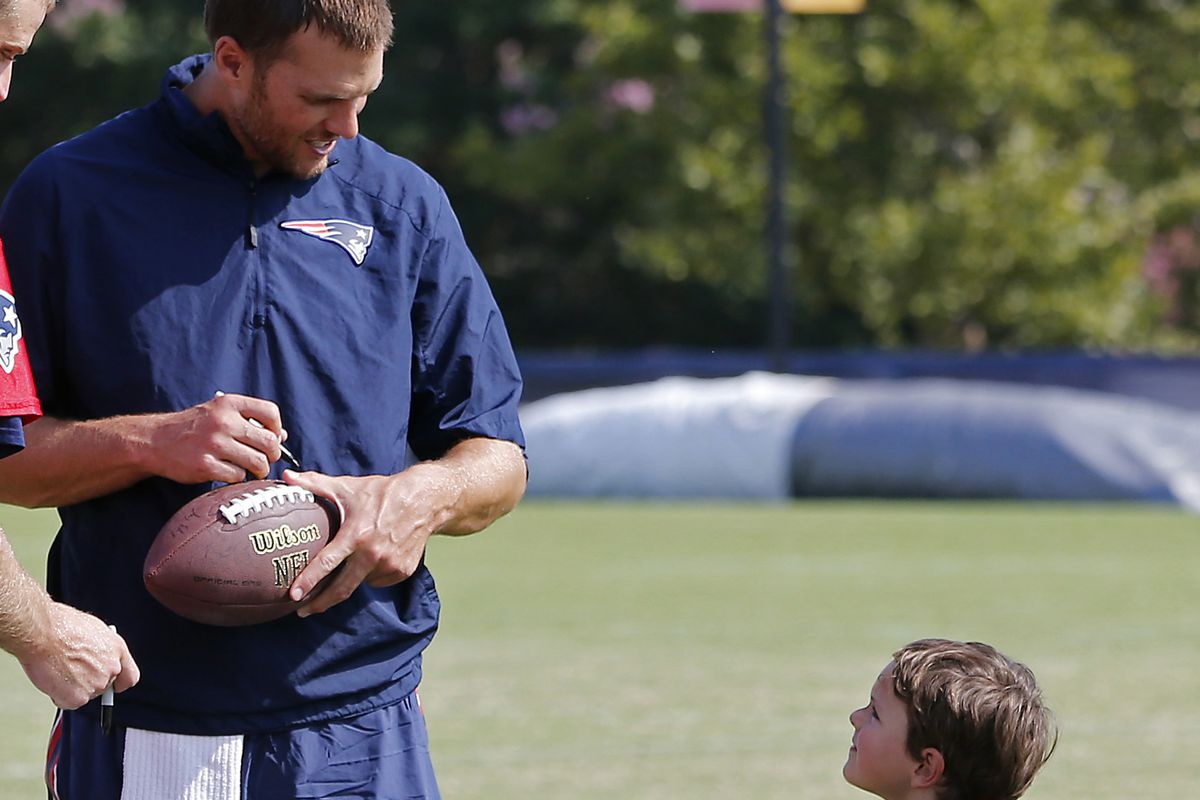 Tom Brady autographs a football at last year's training camp... or as Ted Wells sees it, "bribing" a kid by giving him signed equipment