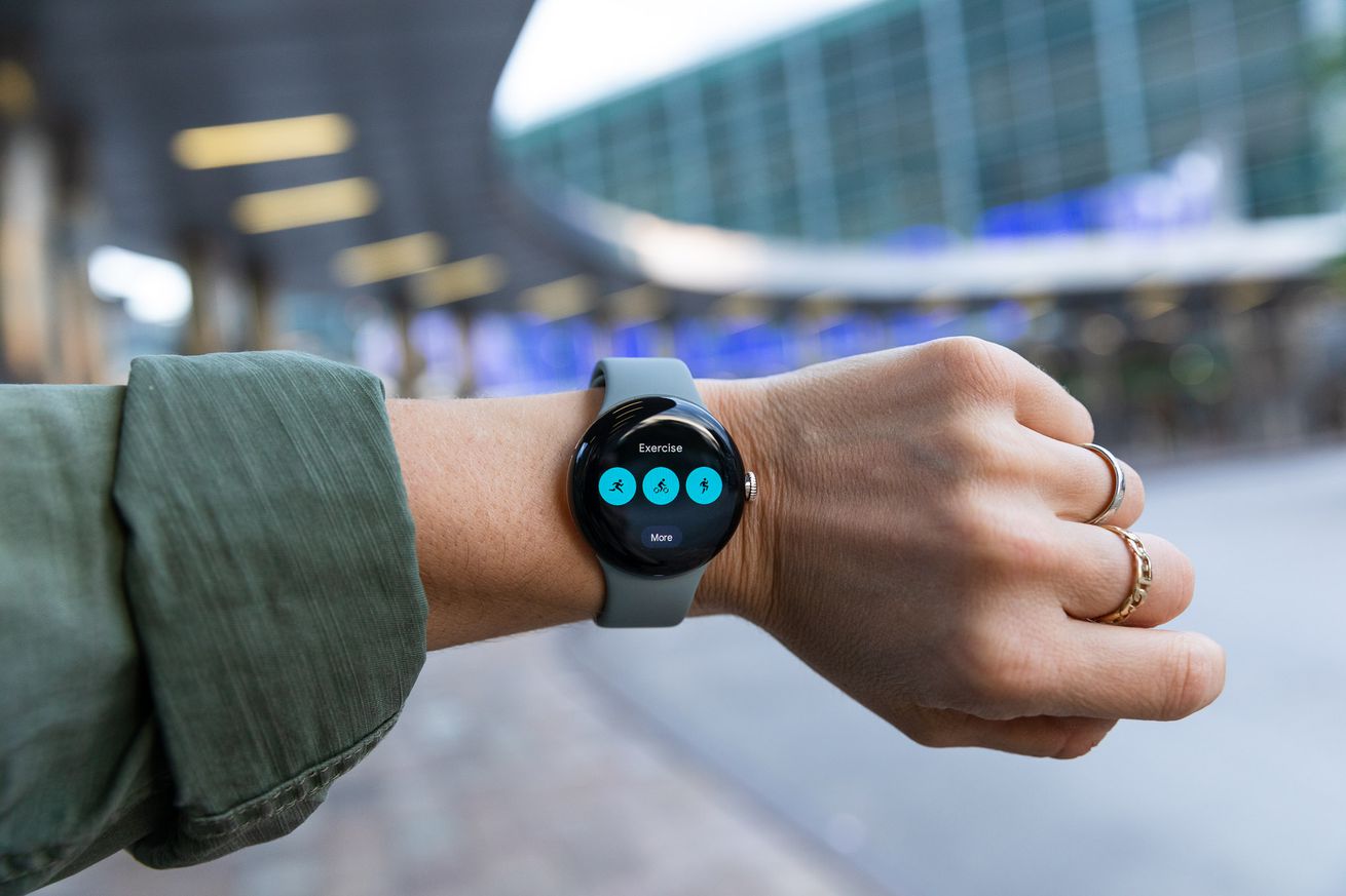 Woman holding up Pixel Watch showing Fitbit exercise widget.