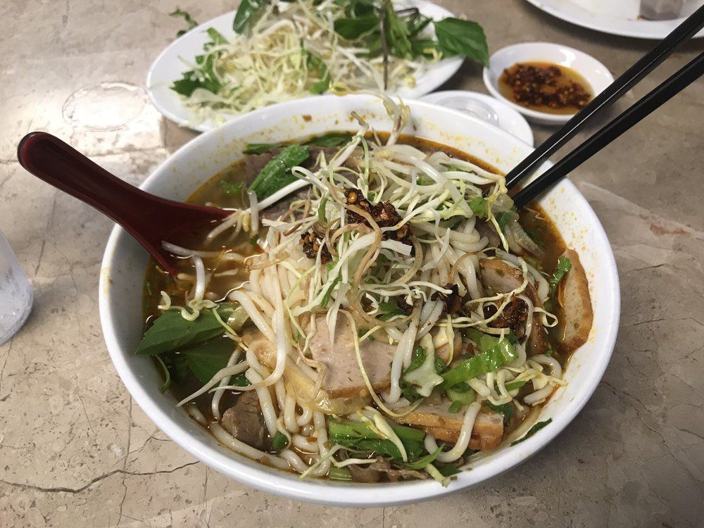 A bowl of Bun Bo Hue pho showered with bean sprouts, basil, and other toppings.